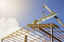 Crane lifting steel beams during metal erection contracting